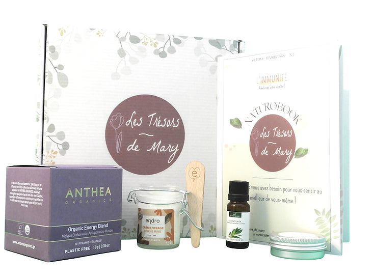 Box Bien-être - Naturopathie & Cosmétique, la boite en carton, le livret, la boite d'infusion, le pot de crème, la spatule, le flacon d'huile essentielle, la boite ronde en métal de baume à lèvre solide sur fond blanc - PBS - Naturopathie & Zéro déchet